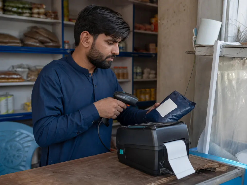 Shop worker scanning stock beside a label printer